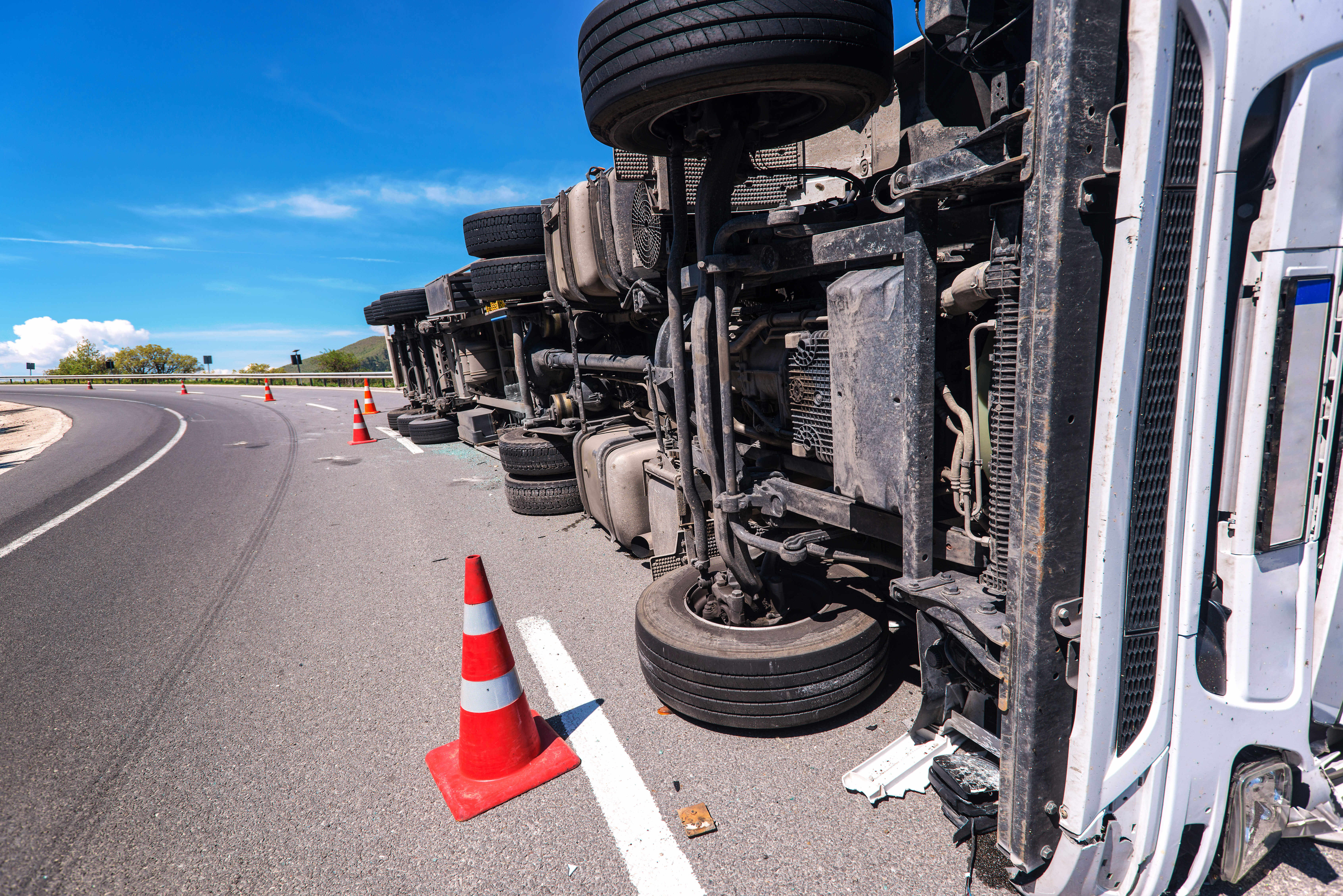 A semi truck that has turned on its side on the free way -- cones are mark the perimeter of the truck accident