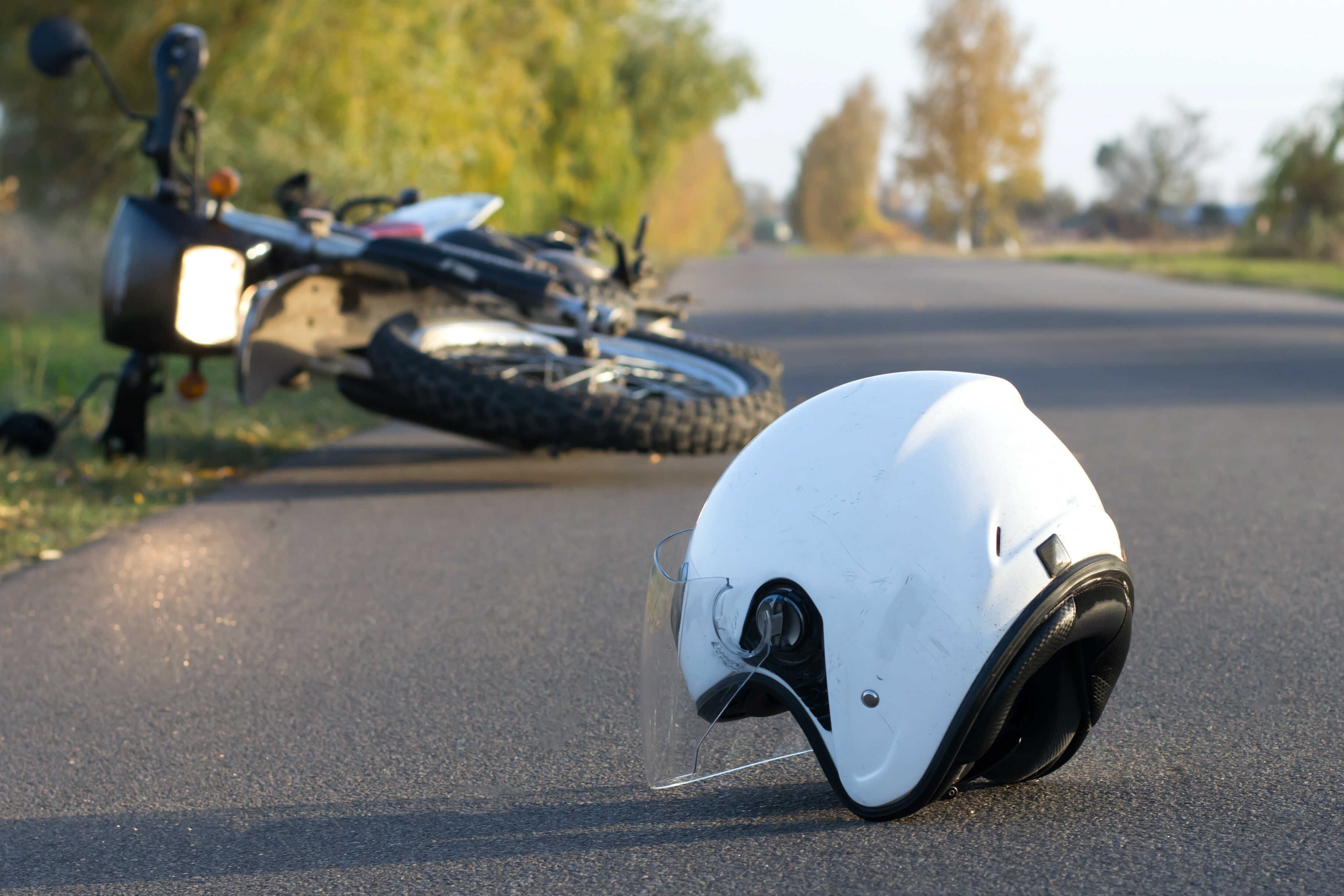 White helmet on asphalt near overturned motorcycle